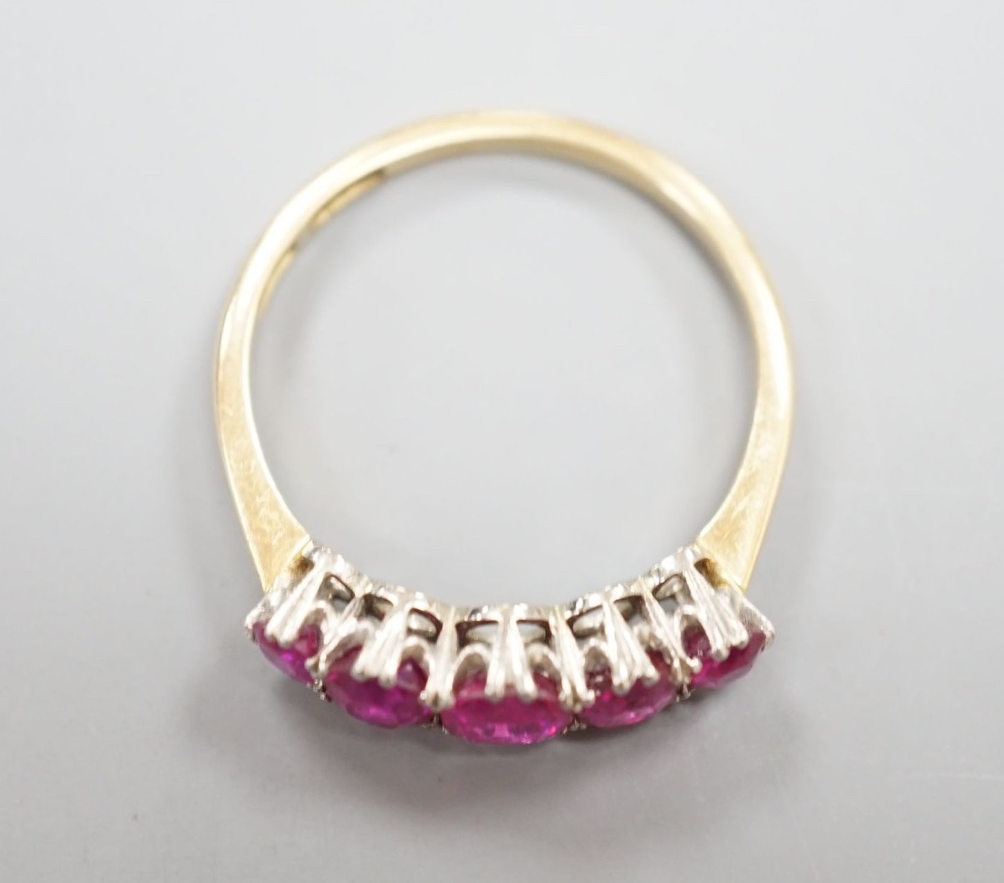 An early 20th century 18ct and plat, graduated five stone ruby set half hoop ring, size Q, gross weight 3.2 grams.